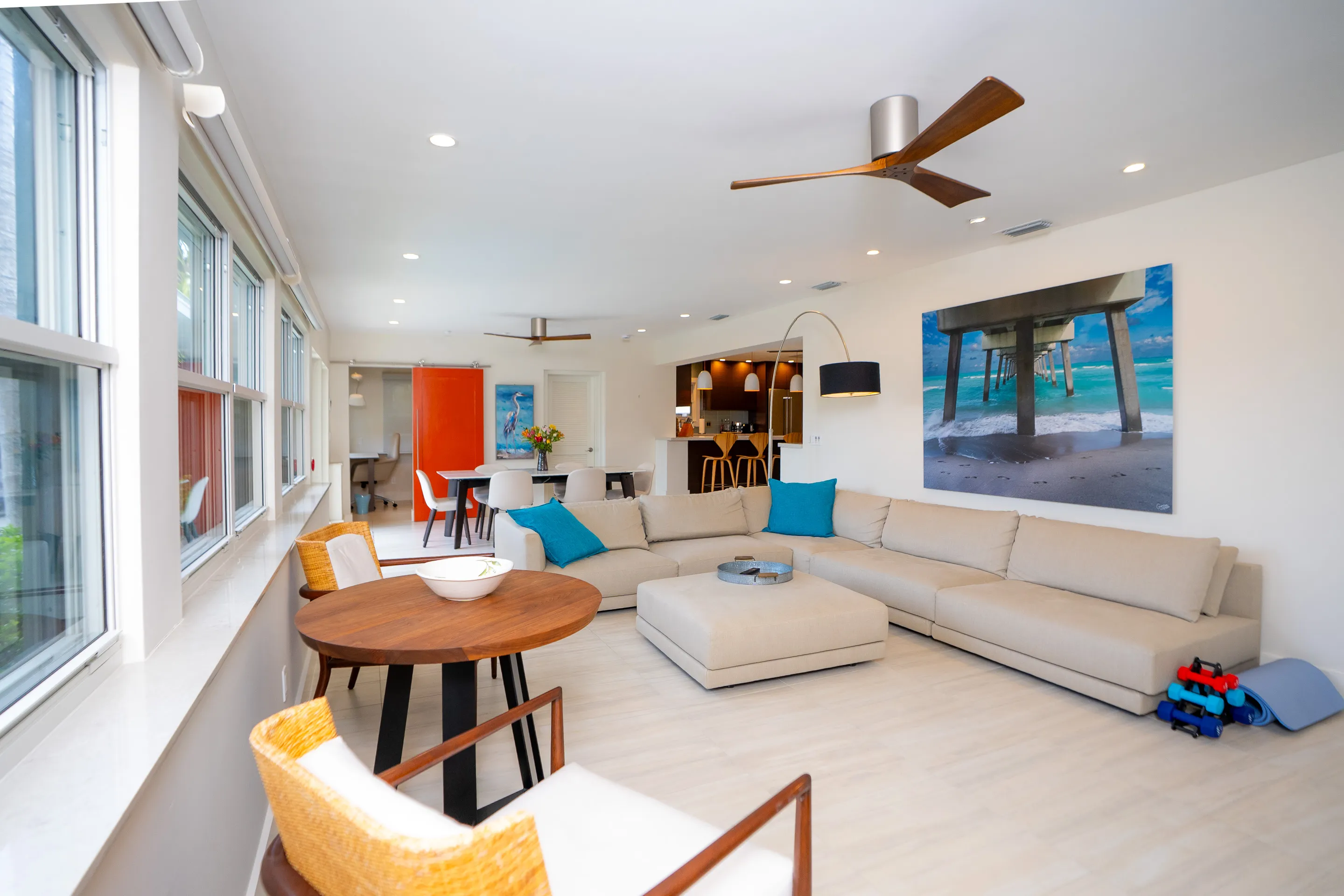 Bright open-plan Key West interior with coastal palette, hardwood floors, and tropical garden views