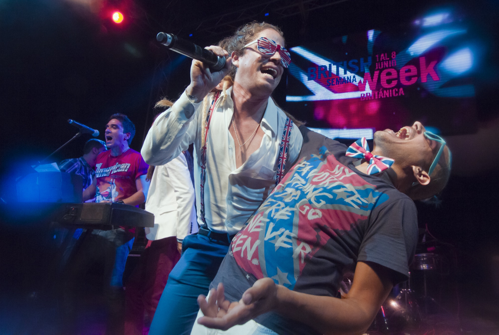 Two singers electrifying a packed stage under colorful concert lighting at British Week festival